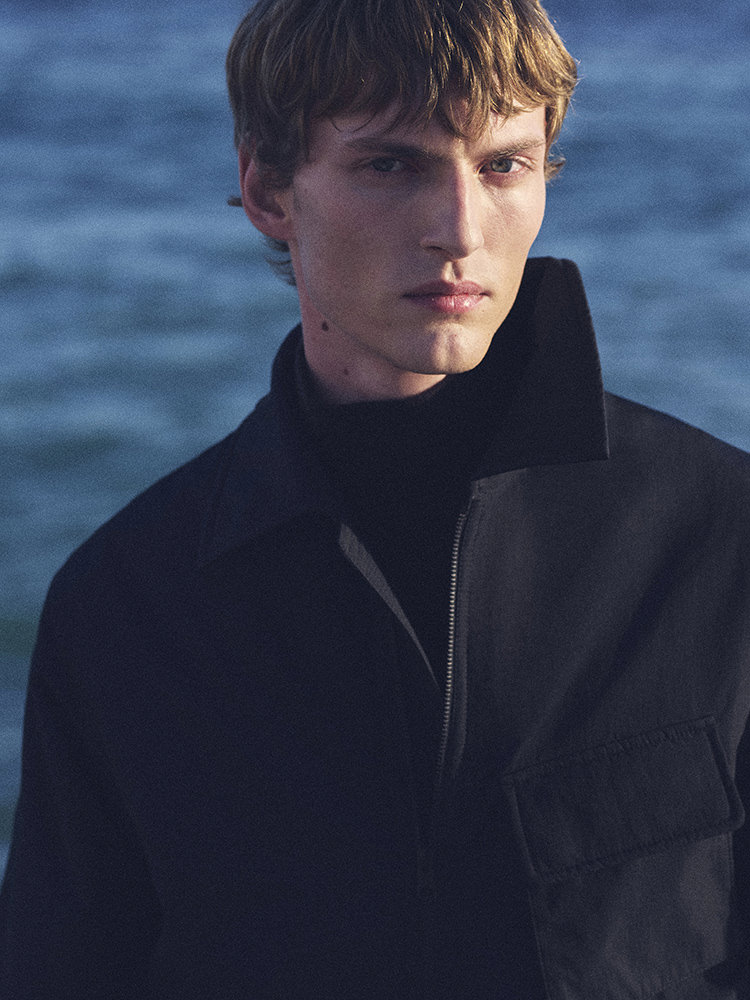 man wearing turtleneck standing on balcony